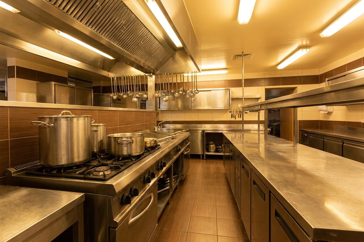 Cozinha industrial com panelas em fogão de grande porte